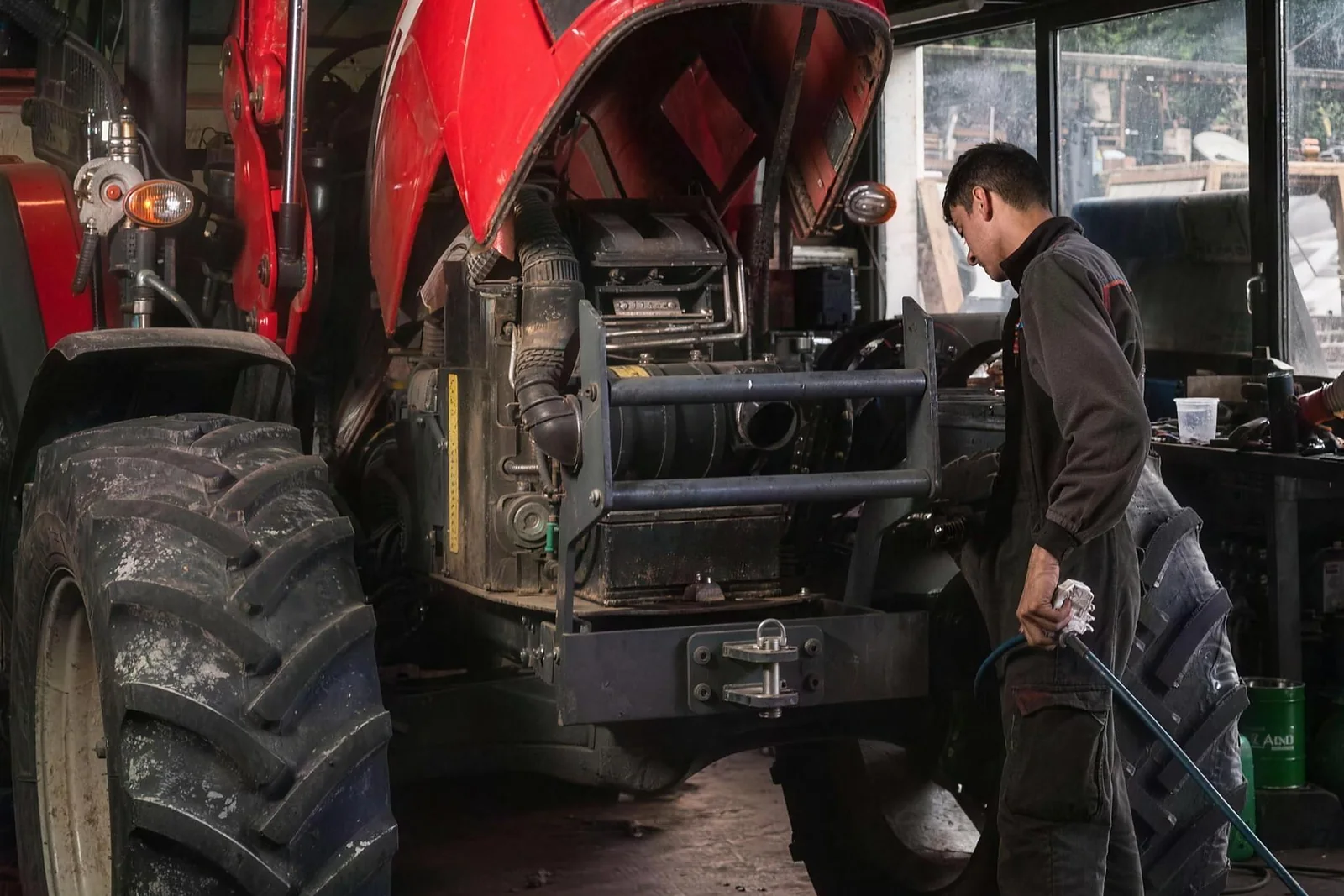 Un technicien à la roue arrière d'un tracteur, flexible à la main